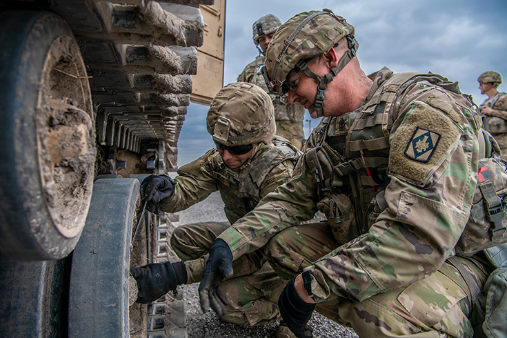 U.S. Army 1st Sgt. Richard McCormick, right, Able Company first sergeant, mentors Pvt. 1st Class Lathan McLeod, a multiple launch rocket system crewmember, on how to properly clear obstructions from a vehicles tracks after prolonged operations at Fort Sill, Okla., March 29, 2019