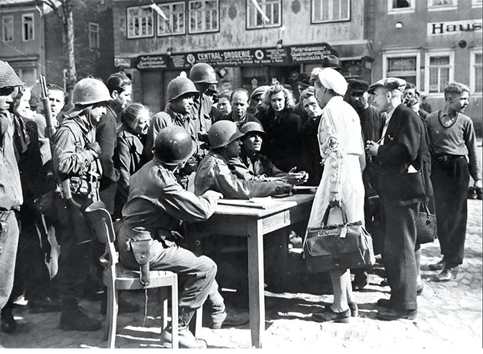 A military government “spearhead” (I Detachment) of the 3rd U.S. Army answers German civilian questions in April 1945 at an outdoor office in the town square of Schlesingen ,Germany.