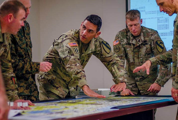 Maj. Lazaro Oliva Jr. (<em>center</em>) shows the potential effects of a tactical decision to other 1st Cavalry Division planners 8 November 2018