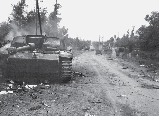 A German self-propelled gun smolders along the road leading from Neuville-au-Plain to Sainte-Mère-Église June 1944 after being destroyed by Pvt. John E. Atchley