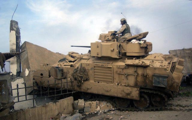 Bradley fighting vehicle turret gunner Sgt. Ramel Colclough fires at Iraqi positions with his 25 mm cannon as his vehicle breaches an obstacle.