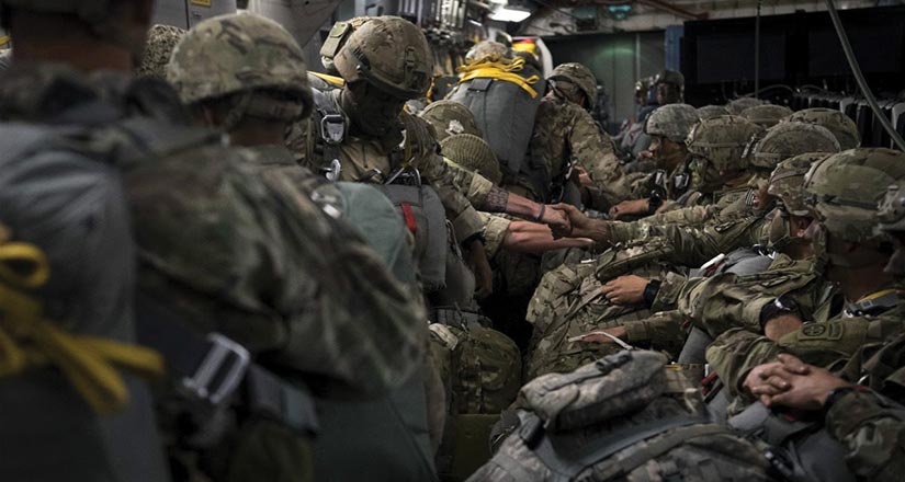 U.S. Army and British Army paratroopers shake hands before jumping from a C-17 Globemaster III over Latvia 8 June 2018 during Exercise Swift Response 18