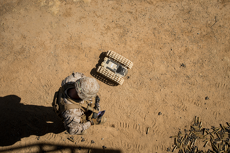 A marine with 3rd Battalion, 5th Marine Regiment looks down at an autonomous “dragon fire” system