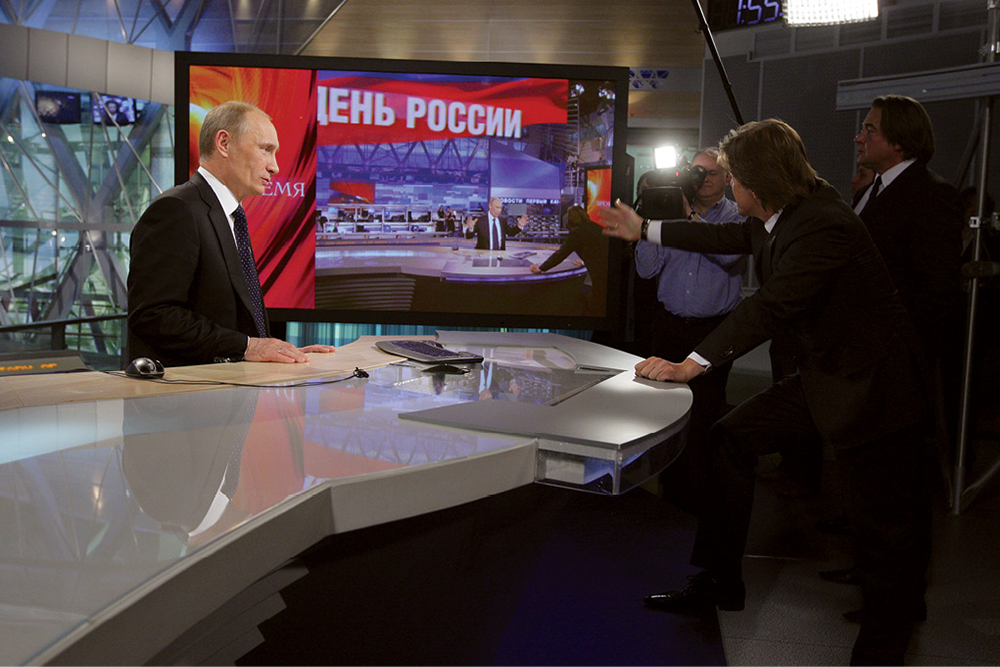 Then Prime Minister Vladimir Putin speaking with Russia-1 deputy CEO Kirill Kleimyonov (second from right) and CEO Konstantin Ernst 3 February 2011 in a news studio at the Ostankino television station in Moscow. Prominent Russian-language news and information channels such as Russia-1 and Russia-24 air all-day programming in Uzbekistan. (Photo by Alexey Druzhinin, Government of the Russian Federation)