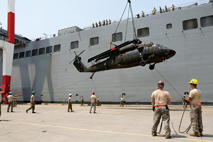 Soldiers guide a UH-60 Black Hawk off the USNS Fisher (T-AKR 301) during port operations
