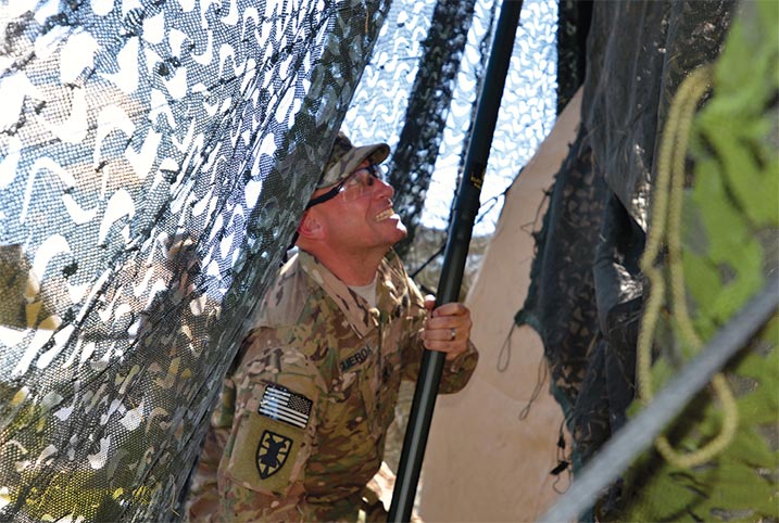 Sgt. 1st. Class Victor Figueroa helps conceal the 13th Expeditionary Sustainment Command's support operations tent