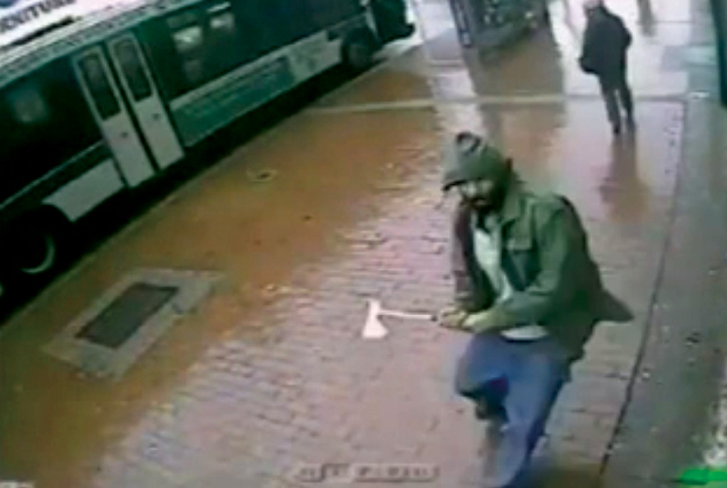 A screenshot from a surveillance camera shows Zale Thompson, labeled a self-radicalized Muslim, raising a hatchet 23 October 2014 moments before striking a group of four uniformed New York Police Department (NYPD) officers in Jamaica, Queens, New York. Thompson was shot dead by two of the officers. (Photo courtesy of NYPD)