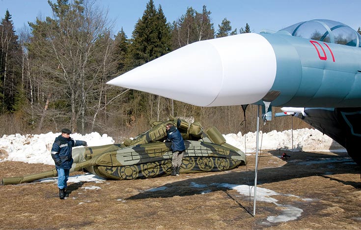 A worker inflates a model of a Russian T-72B tank next to an inflatable dummy of a SU-27 fighter jet 