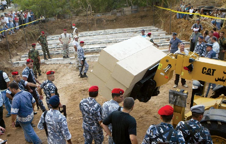 Lebanese soldiers, policemen, and civilians watch as coffins containing the bodies of Islamist militants are transported 4 October 2007 during their burial in Tripoli