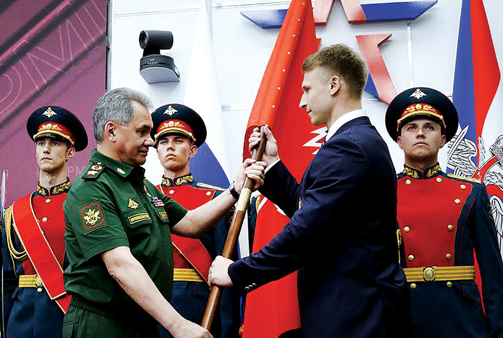 Russian Minister of Defence General of the Army Sergei Shoigu presents the flag to the chief of the Yunarmiya staff, Olympic champion Dmitry Trunenkov, 2 June 2016 during the first rally of the all-Russian military-patriotic social movement Yunarmiya at the military-themed Patriot Park in Moscow. (Photo courtesy of the Ministry of Defence of the Russian Federation)