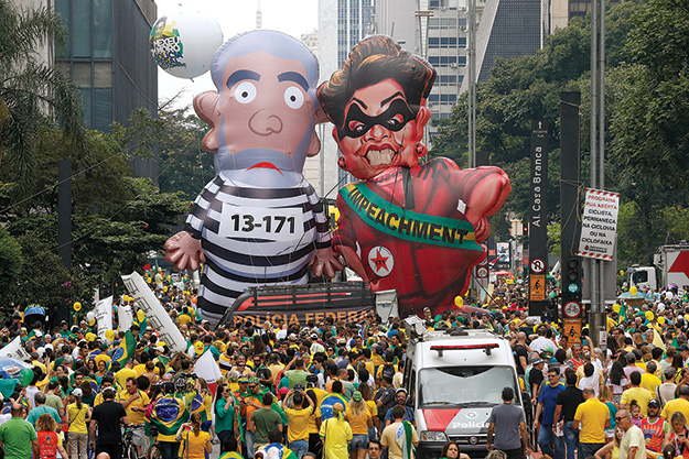 Demonstrators parade large inflatable dolls depicting Brazil’s former President Luiz Inácio Lula da Silva in prison garb and then President Dilma Rousseff dressed as a thief with a presidential sash that reads “Impeachment” 13 March 2016 in São Paulo.