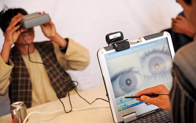 An Afghan Local Police (ALP) officer looks into a biometric eye scanner 18 December 2011 while being processed into the force by members of the Afghan Ministry of Interior in Gizab District, Uruzgan Province, Afghanistan.