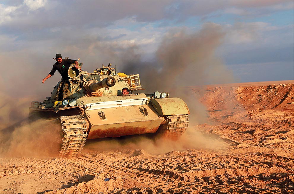 Popular Mobilisation Forces fighters (mostly Iraqi Shia militia) ride in a tank near the Iraqi-Syrian border 26 November 2018 in al-Qaim, Iraq.