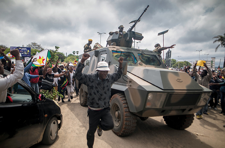 People cheer a passing Zimbabwe Defense Force military vehicle 18 November 2017