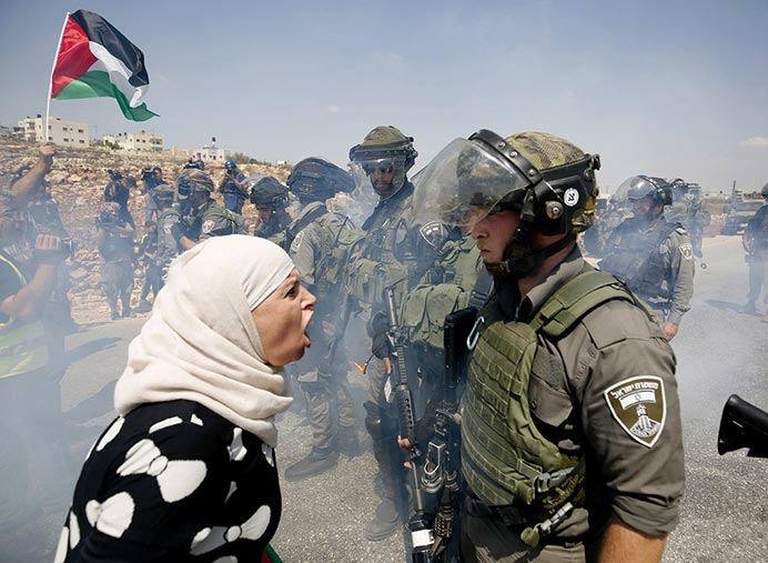 Mulher palestina discute com policial de fronteira israelense