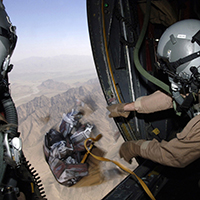 Supervisor de cargas de uma aeronave Hercules C-130 lança caixa com dez mil panfletos de advertência no Afeganistão. As operações psicológicas iniciais no Afeganistão se concentraram em convencer os combatentes inimigos a se renderem.