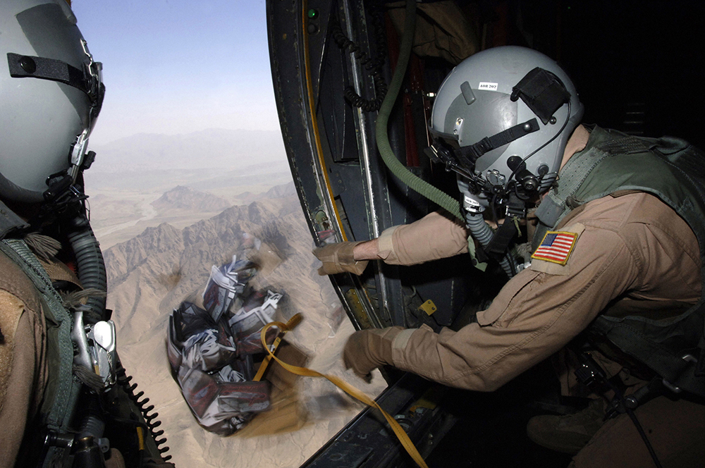 Supervisor de cargas de uma aeronave Hercules C-130 lança caixa com dez mil panfletos de advertência no Afeganistão. As operações psicológicas iniciais no Afeganistão se concentraram em convencer os combatentes inimigos a se renderem.
