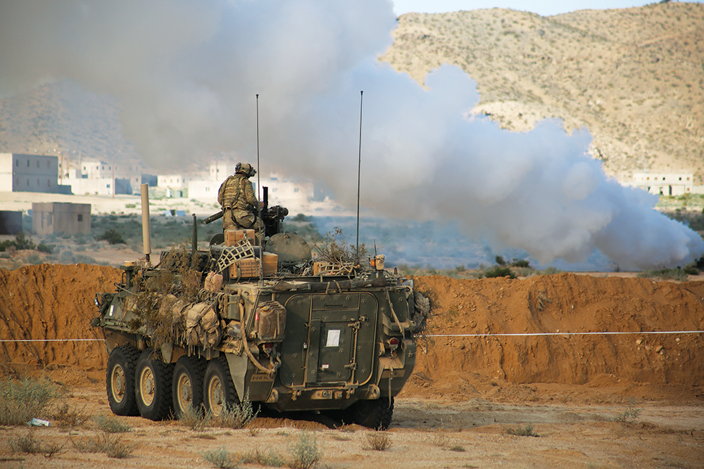 Viatura de combate Stryker da 2a Brigada de Combate, 2<sup>a</sup> Divisão de Infantaria, aguarda uma cortina de fumaça encobrir uma brecha durante o Ciclo de Adestramento 17-09 de Ação Decisiva, no Centro Nacional de Treinamento, em Fort Irwin, Califórnia, 12 Set 17. (Photo by Spc. J. D. Sacharok, Grupo de Operações, Centro Nacional de Treinamento, Exército dos EUA)