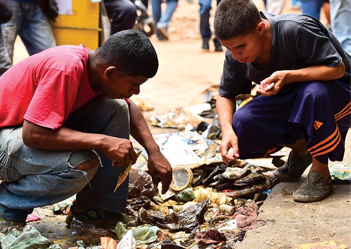 Jovens buscam por comida no lixo despejado