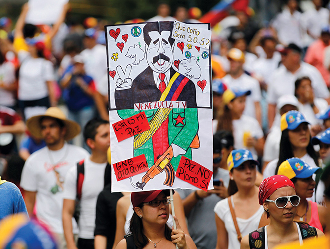 Um manifestante antigoverno segura um cartaz com uma caricatura do Presidente venezuelano Nicolas Maduro