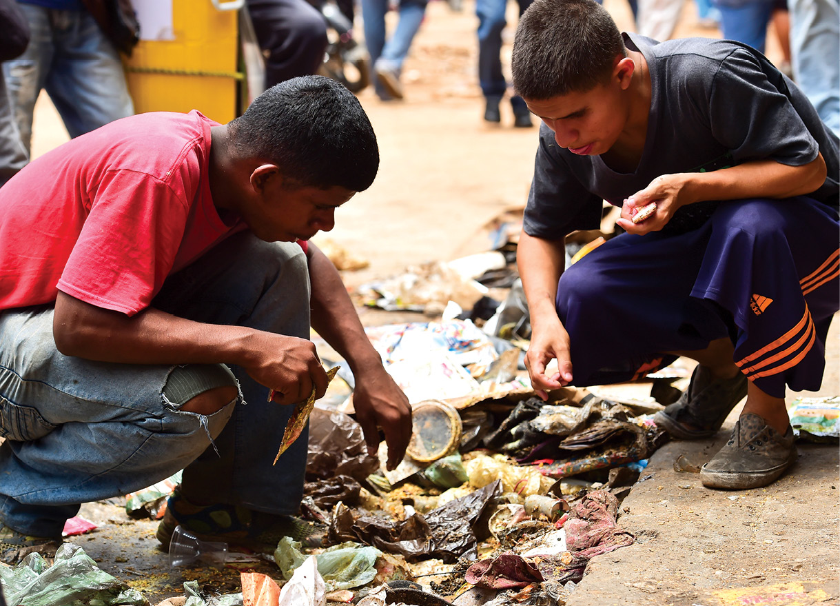 Personas buscan comida en un basurero en las afueras de un supermercado saqueado el 21 de abril de 2017, en la parroquia de El Valle, Caracas, Venezuela, después de demostraciones en contra del presidente venezolano Nicolás Maduro. (Foto: Ronaldo Schemidt, Agence France-Presse)