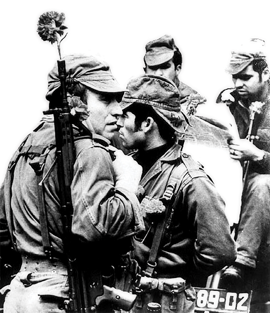 Soldados portugueses muestran claveles después de un golpe de estado militar exitoso conocido como la «Revolución de los Claveles» en Lisboa, Portugal, 25 de abril de 1974. El pueblo portugués, celebrando el golpe casi sin derramamiento de sangre, colocó claveles en los uniformes de los soldados o flores en el cañón de los fusiles. (Foto cortesía del Centro de Documentação–Universidade de Coimbra)