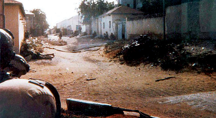 El personal de la Fuerza de Tarea Ranger se oculta al lado de edificios cerca de sitio donde se estrelló un helicóptero, 3 de octubre de 1993, en Mogadiscio, Somalia. Esta es la única foto publicada del campo de batalla durante el enfrentamiento. (Foto: cortesía del Ejército de EUA)