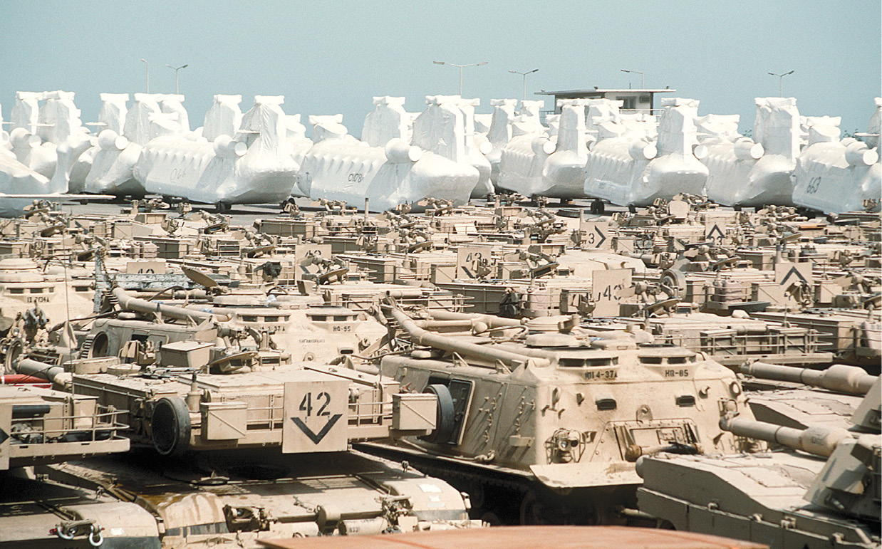 Vehículos blindados y helicópteros cubiertos esperan ser transportados a Estados Unidos el 17 de junio de 1991 después de participar en la operación Desert Storm. El gran éxito de los esfuerzos logísticos durante la guerra se debe en parte al nombramiento del teniente general William «Gus» Pagonis como comandante de las operaciones de sostenimiento. (Foto: Teniente Gary W. Butterworth, Armada de Estados Unidos)