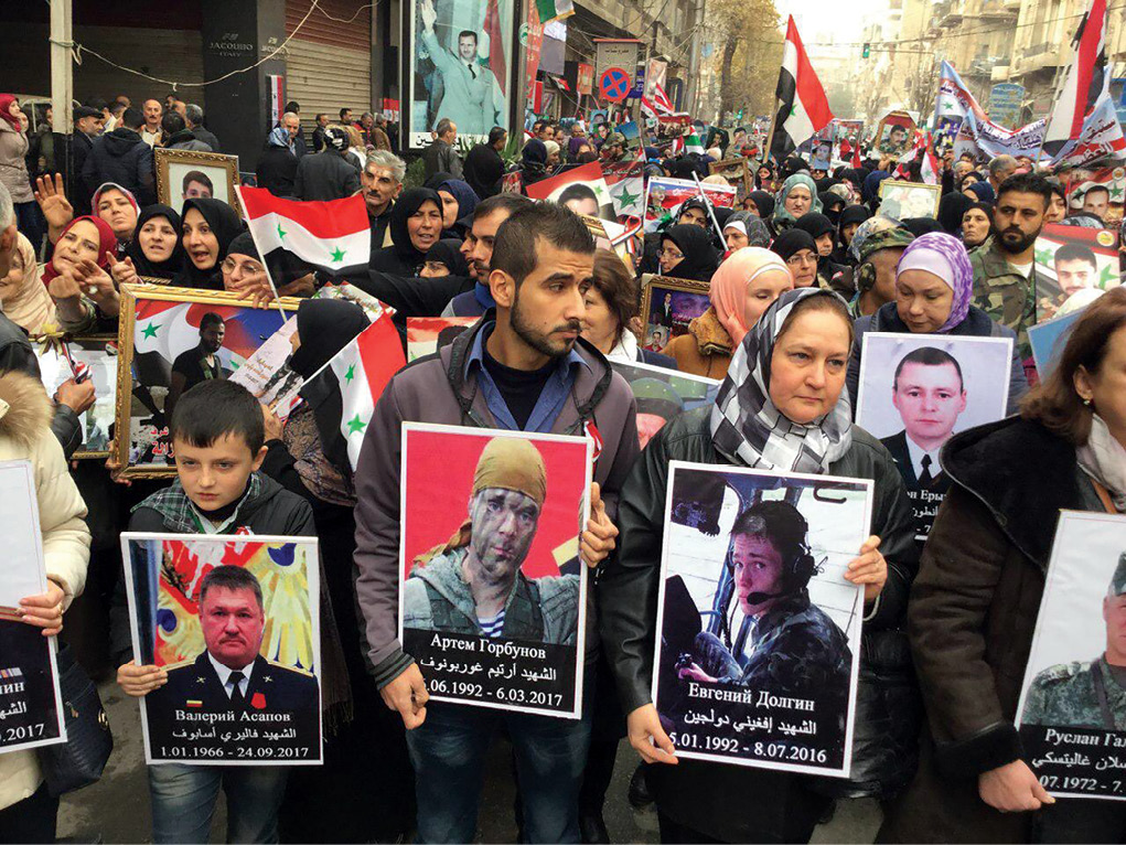 En un desfile en la ciudad de Alepo, Siria, ciudadanos sirios muestran fotos de soldados rusos que murieron en combate en Siria, 22 de diciembre de 2017. Los sirios expresaban su aprecio por las contribuciones de la Federación Rusa durante la celebración del primer aniversario de la captura de Alepo. (Foto cortesía de la cuenta Twitter de la Embajada de Rusia, @EmbassyofRussia)