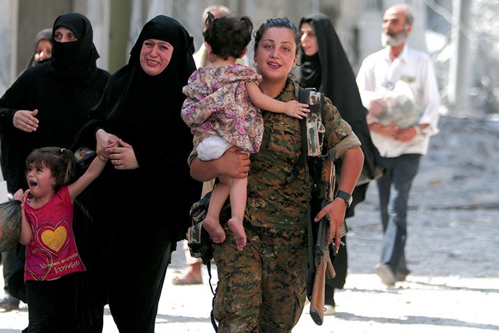 Una combatiente de las Fuerzas Democráticas Sirias (FDS) ayuda a refugiados civiles