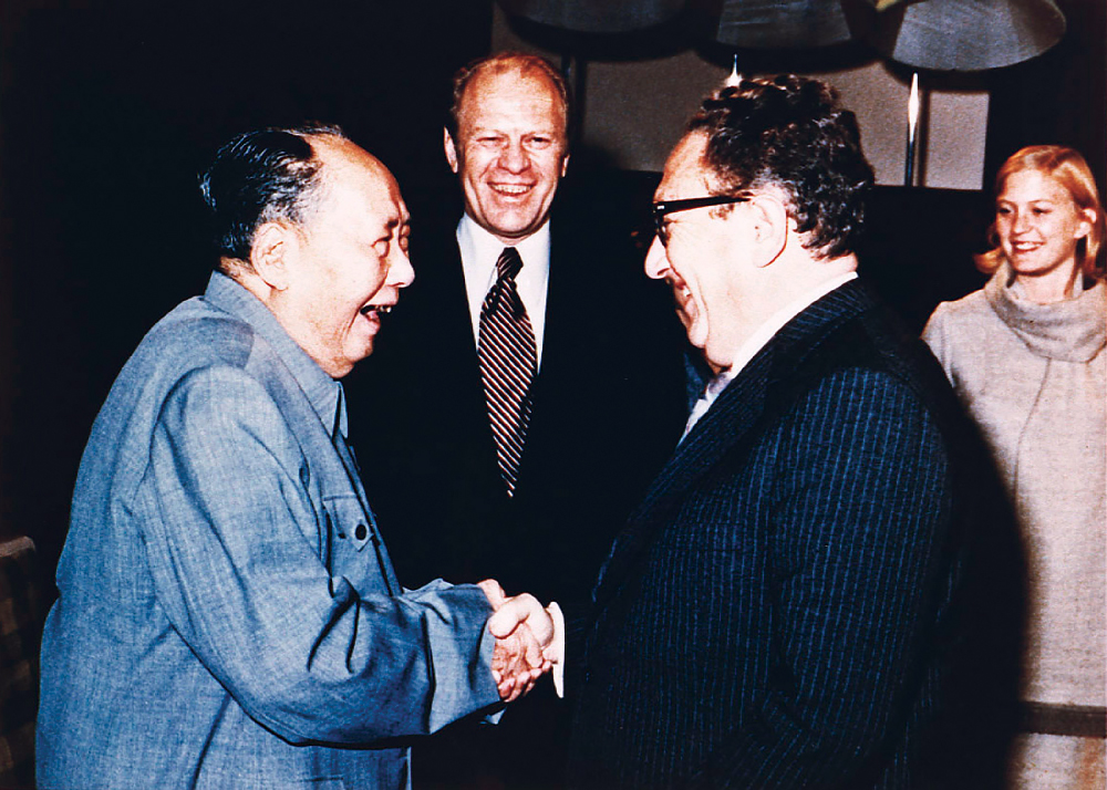 El presidente Gerald Ford (centro) y su hija Susan observan al secretario de Estado, Henry Kissinger, estrechar la mano del presidente del Partido Comunista de China, Mao Tse-Tung, el 2 de diciembre de 1975 durante una visita a la residencia del presidente. (Fotografía cortesía de la Biblioteca Gerald R. Ford)
