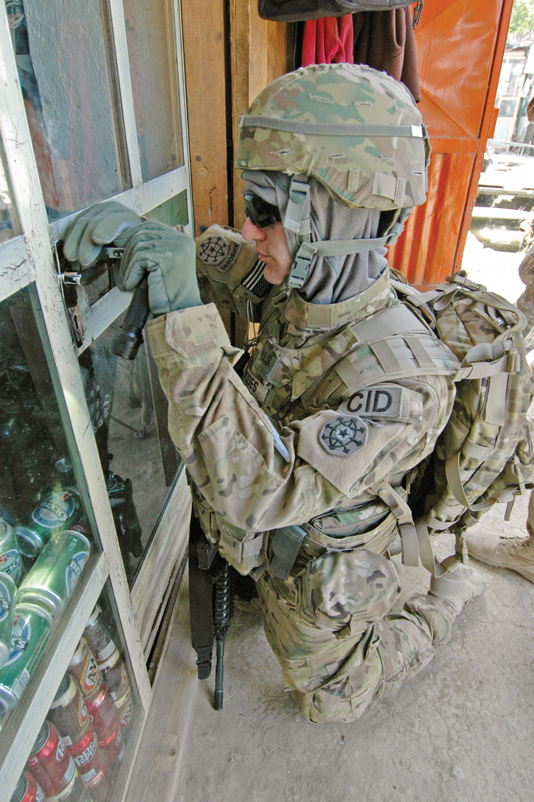 Special Agent Russell Rhodes, a digital forensic examiner serving with the 10th Military Police Battalion (CID) (Airborne) in Bagram, Afghanistan, in August 2011, picks the lock of a store believed to be selling stolen U.S. government property. (Photo by Colby T. Hauser)