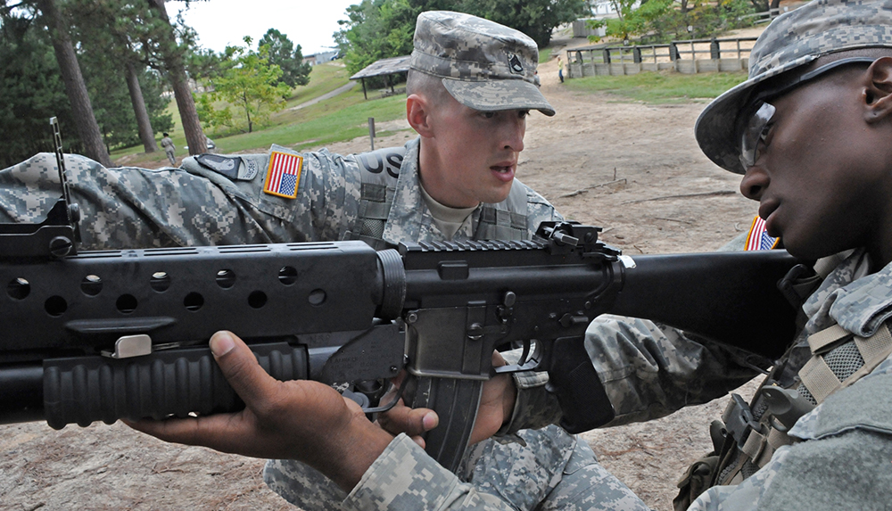 Staff Sgt. Jonathan Miller, 787th Military Police Battalion, 14th MP Brigade, Fort Leonard Wood, Mo., teaches a Soldier how to fire an M203 grenade launcher. Miller is competing to be drill sergeant of the year.