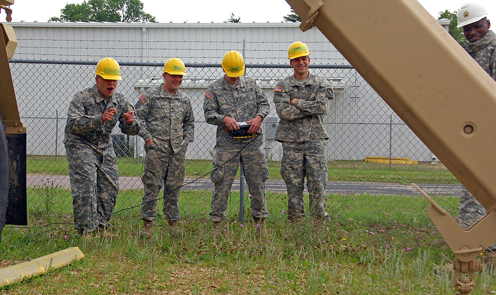 Students working with Staff Sgt. James Rumph, upper right, laugh at the struggle of trying to precisely control the operation of an arm of a HEMTT at Fort McCoy.