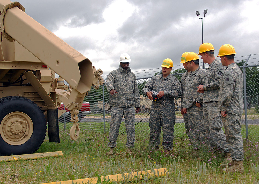 Staff Sgt. James Rumph, left, instructs students on the operation of an arm of a HEMTT at Fort McCoy.