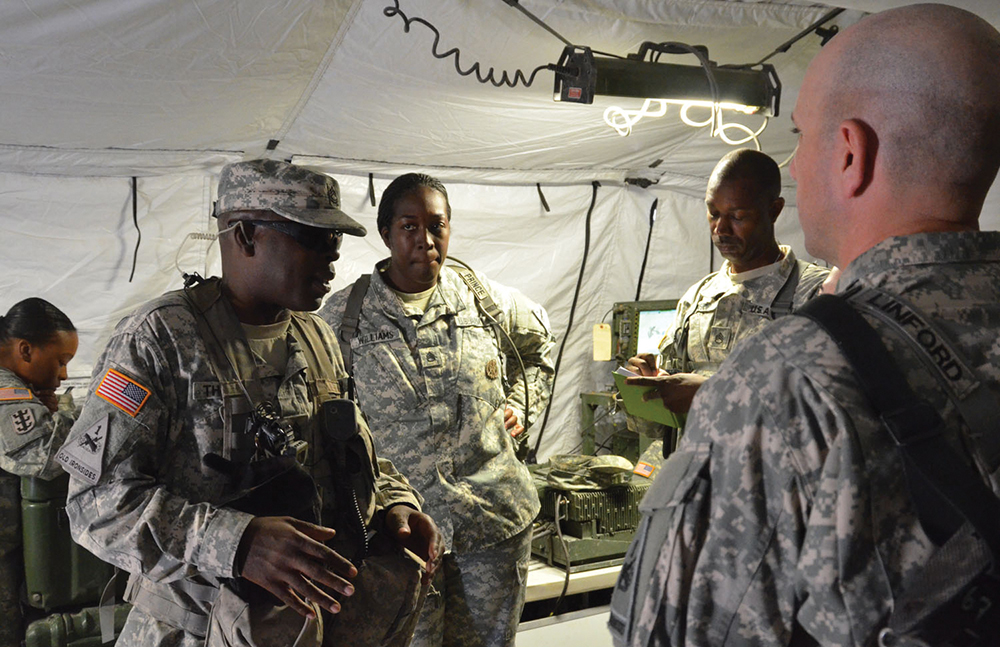 Sgt. 1st Class Marlon Thomas, left, speaks with Soldiers from the 4th Armored Brigade Combat Team of Fort Bliss, Texas, during the unit’s training rotation at the National Training Center at Fort Irwin, Calif., in September 2014. Thomas is a senior brigade sustainment battalion trainer for the Goldminers Team of the NTC’s Operations Group. (Photo by Pablo Villa / NCO Journal)