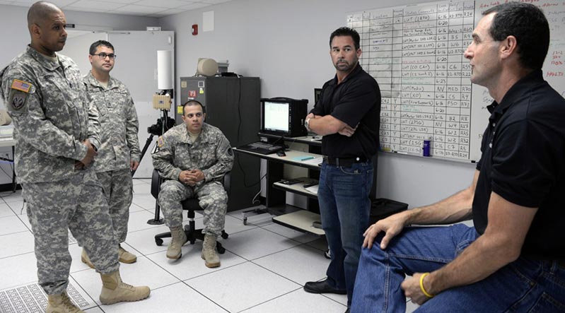 >Army Research Lab’s Sgt. Maj. Kevin M. Connor (<i>from left</i>), Staff Sgt. Joseph A. Pike and Staff Sgt. Jose Roldan Jr. listen to a presentation on open software radios in August from engineer Jason Enslen