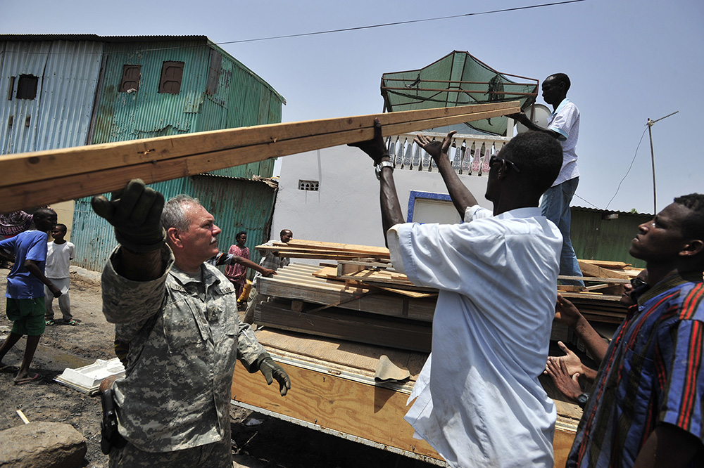 Staff Sgt. Wayne Teegardin, from the 478th Civil Affairs Battalion, Combined Joint Task Force–Horn of Africa, unloads lumber in the Boulas commune of Djibouti City on Aug. 12, 2009. The lumber was used to rebuild 21 homes destroyed in a fire. (Department of Defense photo by Navy Mass Communication Specialist 2nd Class Jesse B. Awalt)