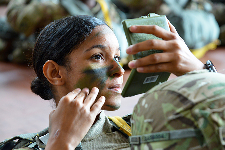 U.S. Army Paratrooper assigned to the 54th Brigade Engineer Battalion, 173rd Airborne Brigade, puts the finishing touches to her face paint camouflage
