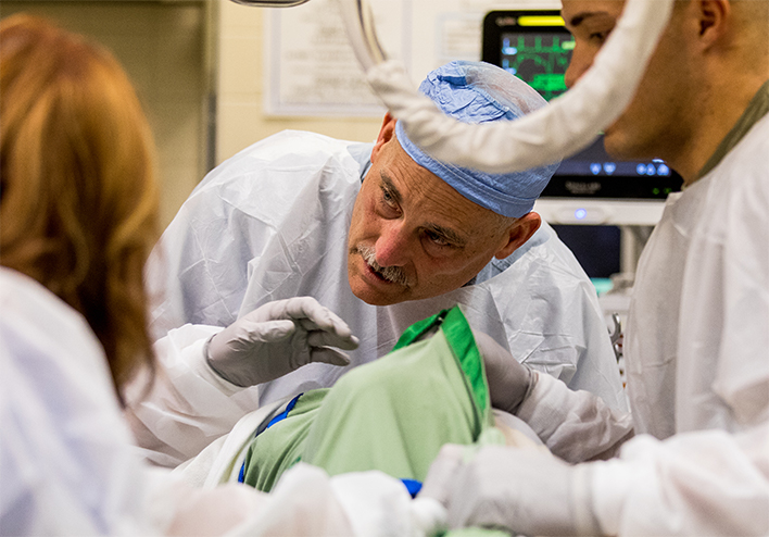 Col. (Dr.) Stephen Bolt leans in close to speak to his patient as he assesses his injuries at Madigan Army Medical Center's Emergency Department