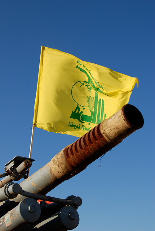 A Hezbollah flag flying over an abandoned artillery piece