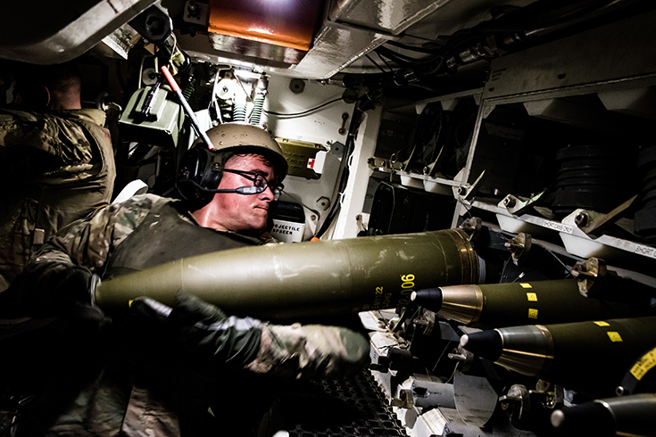 U.S. Army Spc. Brett Kelly, an artillery cannon gunner assigned to Delta Battery, 1st Battalion, 5th Field Artillery Regiment, 1st Armored Brigade Combat Team, hefts a 155mm artillery round into an ammo rack