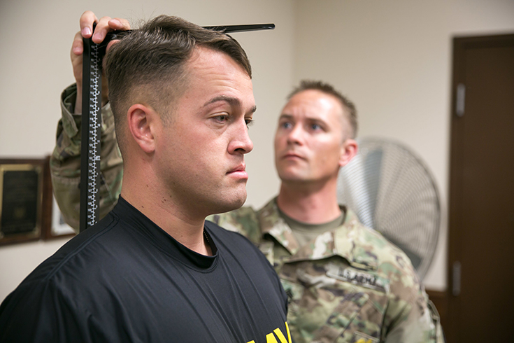 U.S. Army Sgt. 1st Class Joshua Weaver measures height and weight