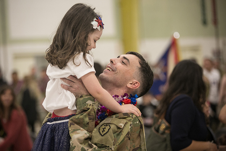 A U.S. Army Soldier assigned to the Hillclimbers, 3rd Battalion, 25th Aviation Regiment (General Support Aviation Battalion) reunites with family during a welcome home ceremony