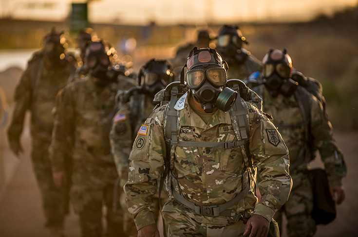 U.S. Army Command Sgt. Maj. Craig Owens leads a team-building ruck march while wearing protective masks along with command sergeants major from his brigades and battalions