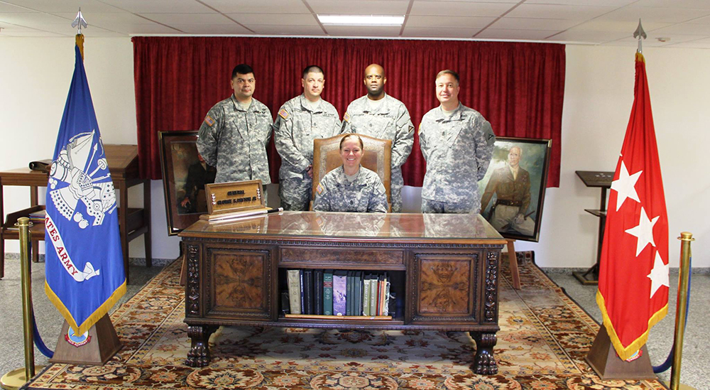 U.S. Army Europe’s command sergeant major, Command Sgt. Maj. Sheryl Lyon, sits at “The Patton Desk” at the main entrance to the 7th Army NCO Academy in Grafenwoehr, Germany. The desk belonged to Gen. George S. Patton during World War II. (Photo courtesy of 7th Army NCO Academy)