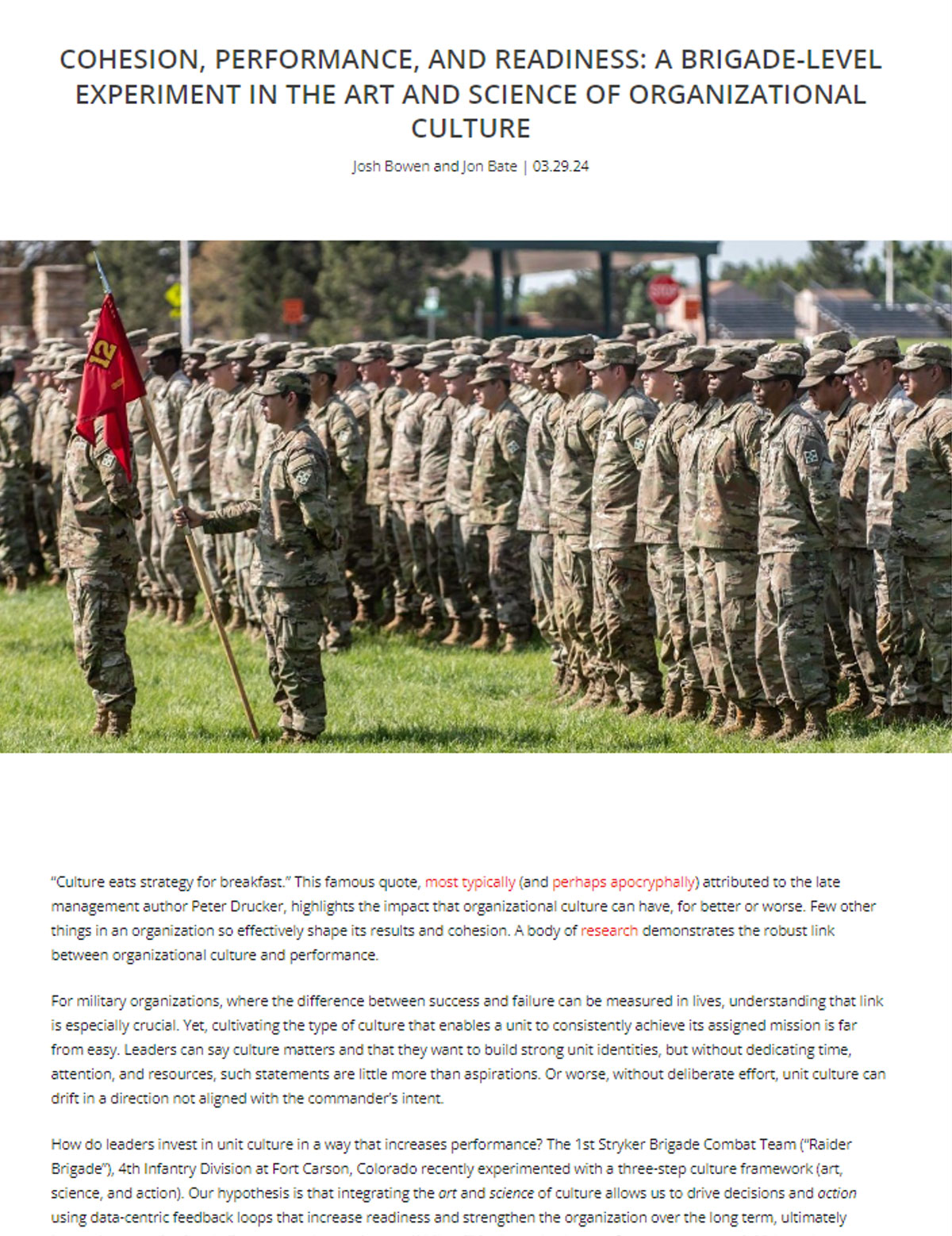 A group of military personnel in camouflage gear receives medical training outdoors, with one demonstrating the use of medical equipment.