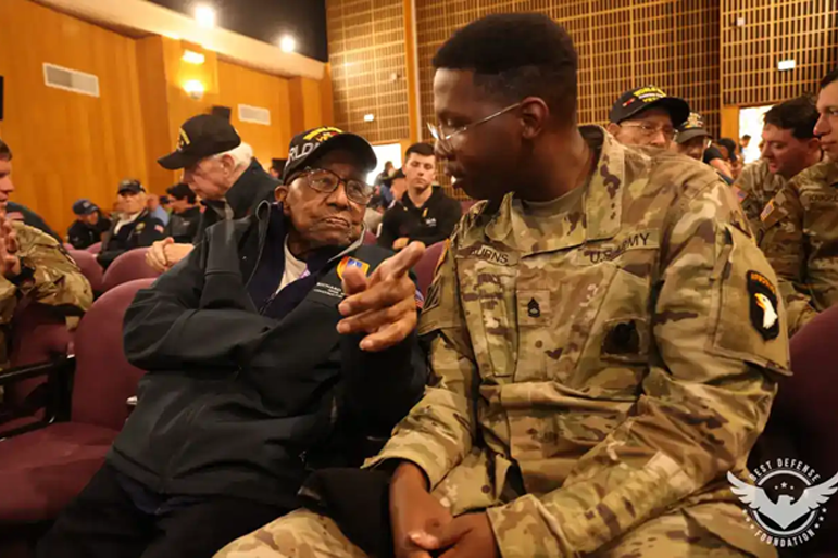 A “Screaming Eagle” soldier from the 101st Airborne Division (Air Assault) discusses combat experiences with World War II veteran during the 79th Anniversary of D-Day held at Normandy, France.