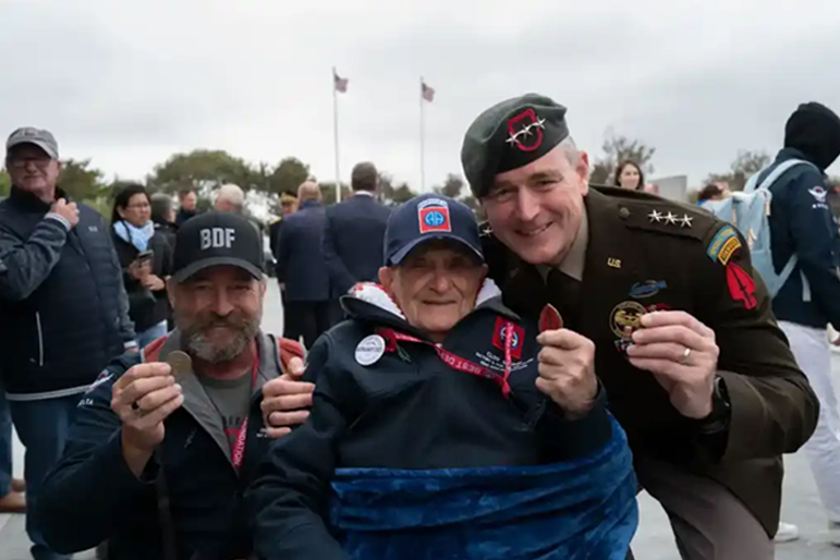 A U.S. Army general gives a World War II veteran a unit coin during the 79th Anniversary of D-Day held at Normandy, France