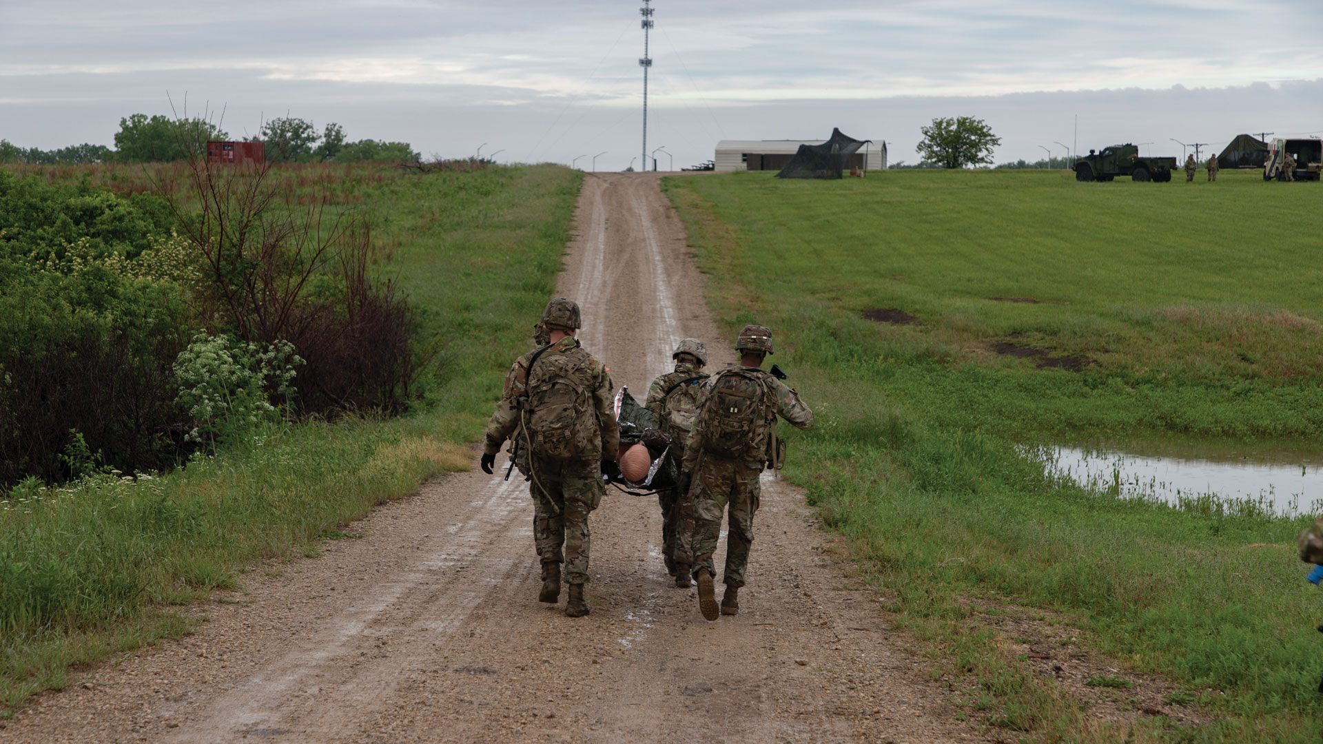 Soldiers in camouflage uniforms walking down a dirt road simulated a casualty movement